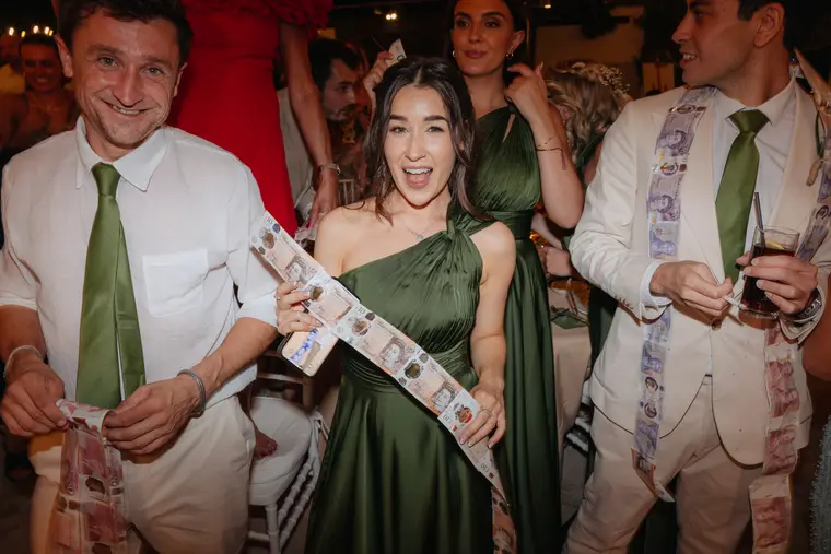 Bridesmaid and groomsmen draped in banknote garlands during the money dance