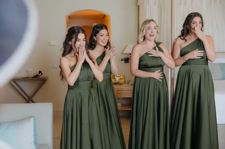 Bridesmaids in green satin gowns gasping as they see the bride