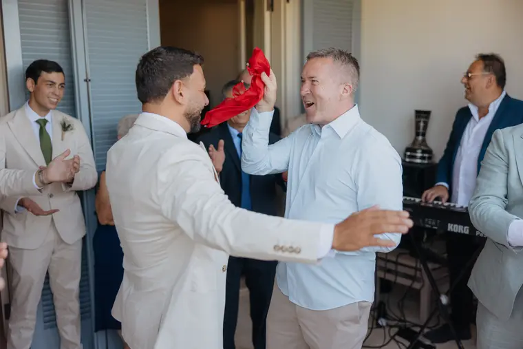 Andrew laughing as a guest waves a red ribbon during the blessing