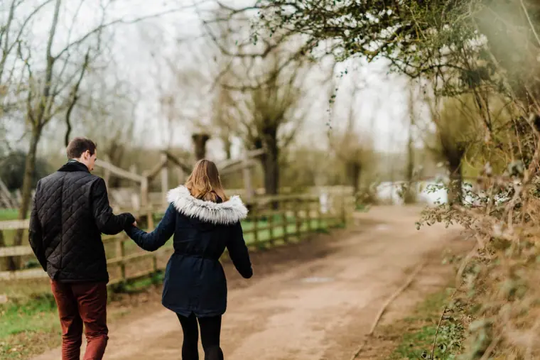 Couple walking hand in hand along a lakeside path