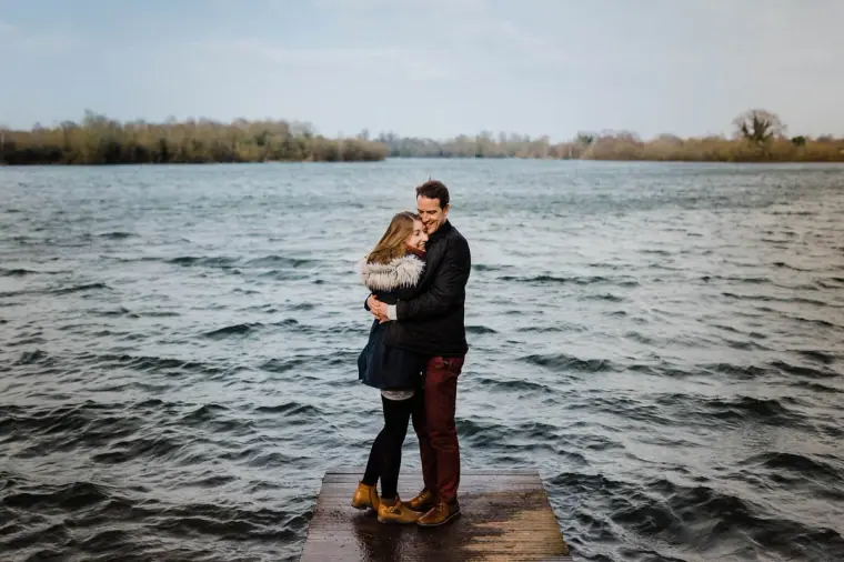 Jana and Alex embracing on a jetty on the lake at Dinton Pastures