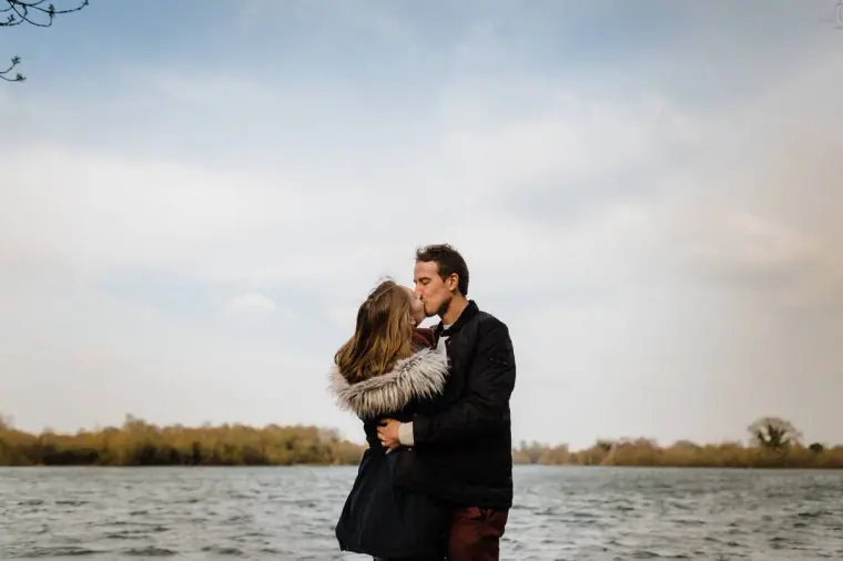 Alex kissing Jana's forehead with the lake behind them