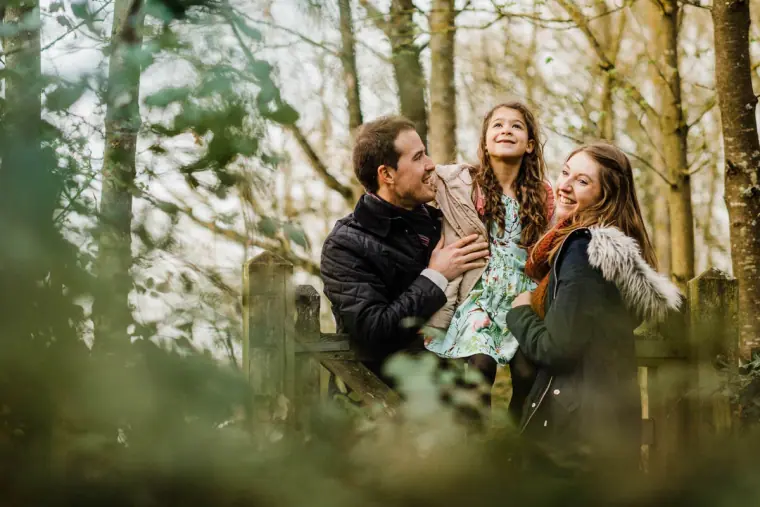 Couple laughing in the woods with a young girl between them