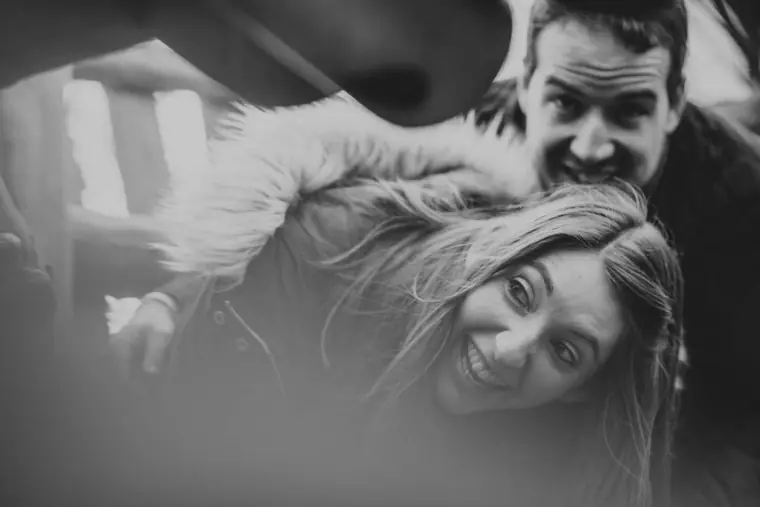 Black-and-white photo of the couple laughing together in a play tunnel