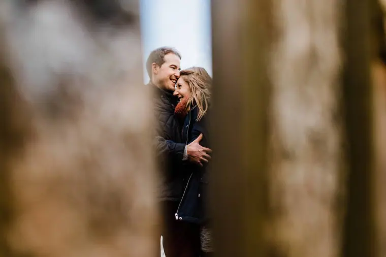 Couple embracing, glimpsed between wooden posts