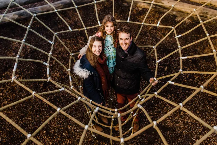 Overhead view of the couple and a young girl in a rope spider-web climbing net