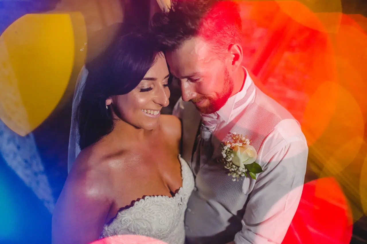 Laura and Lee smiling close together amid colourful light flares at Royal Apollonia, Limassol