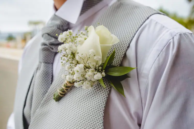 Groom's white rose and gypsophila buttonhole on a grey waistcoat