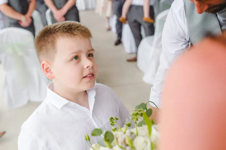 Page boy in a white shirt holding a posy at the ceremony