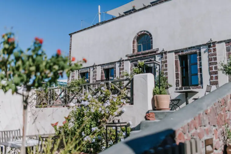 Whitewashed house with arched windows and a flowering tree on a hillside lane