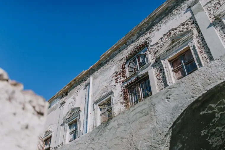 Weathered white mansion facade against a deep blue sky