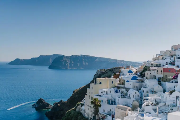 Clifftop village of white houses tumbling towards the caldera, islands beyond