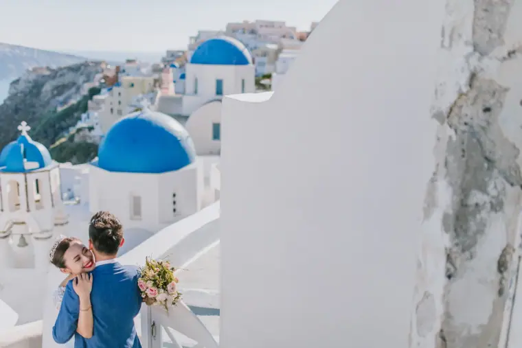 Couple embracing on a white terrace overlooking Santorini's blue domes and the sea