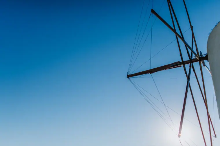 Traditional windmill sails silhouetted against a bright blue sky