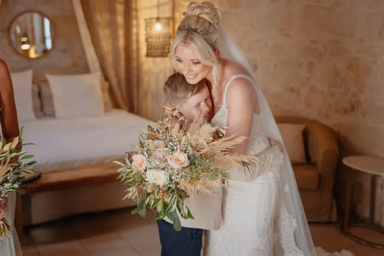 Bride hugging a young page boy in the bridal suite