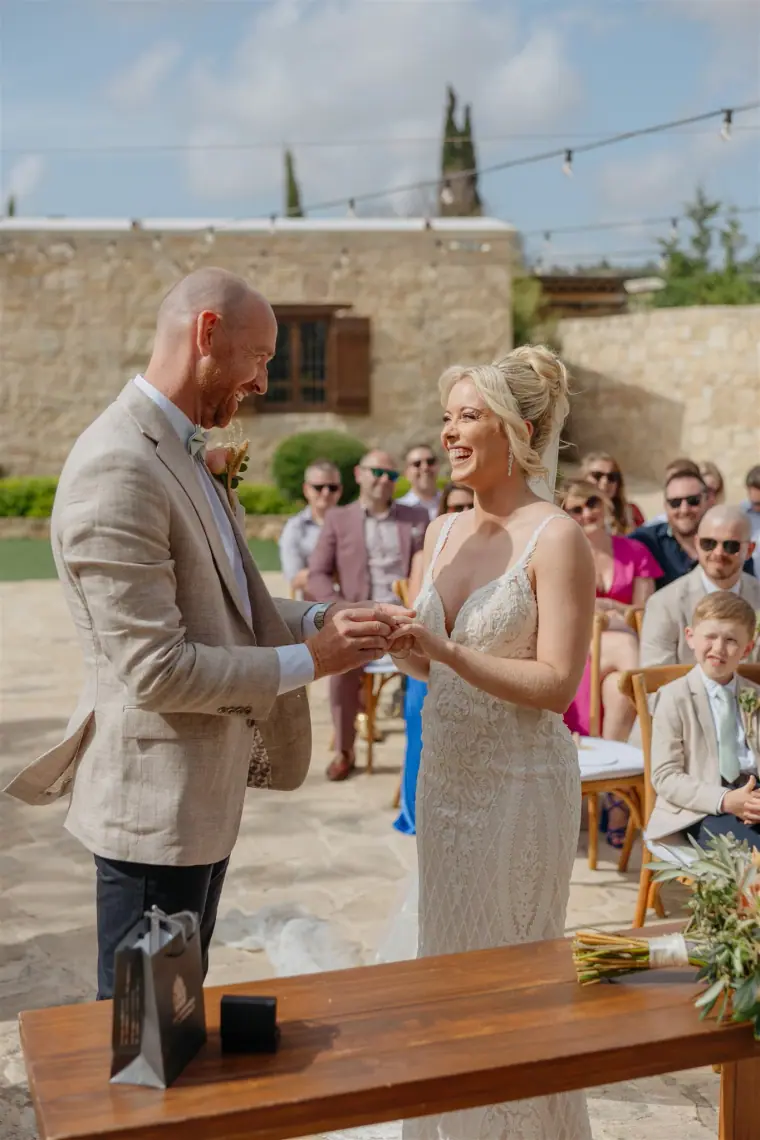 Ben placing the ring on Sarah's finger at the ceremony table