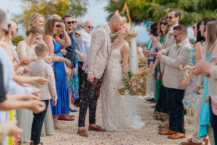 Guests throwing petals as the newlyweds walk back down the aisle