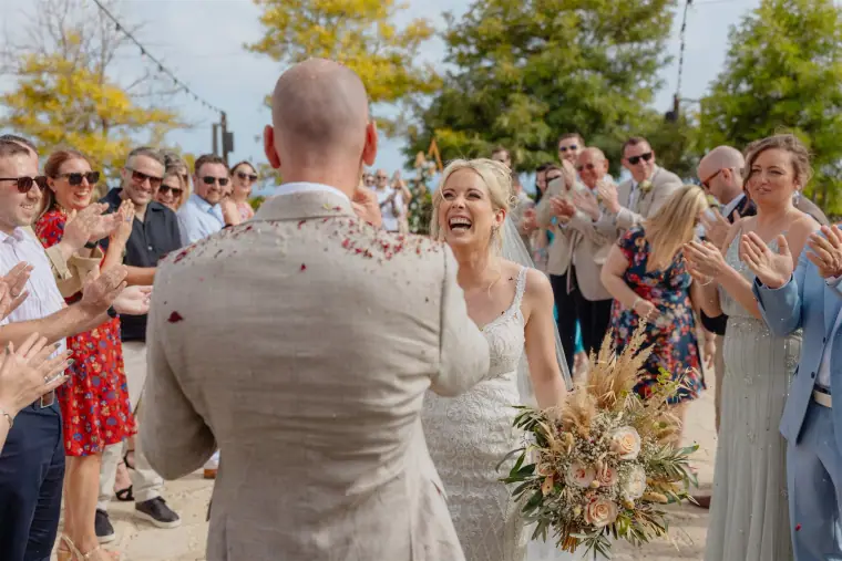 Sarah laughing as guests shower the couple with petals