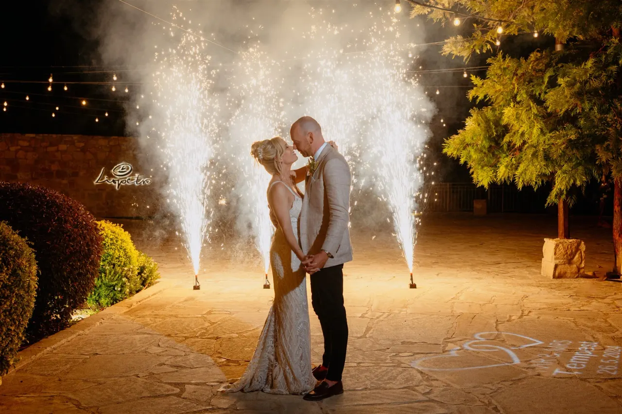 Sarah and Ben kissing between cold-spark fountains at night at Liopetro