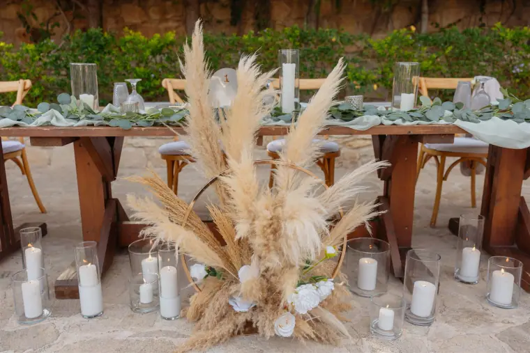 Pampas grass arrangement and pillar candles beneath the reception tables