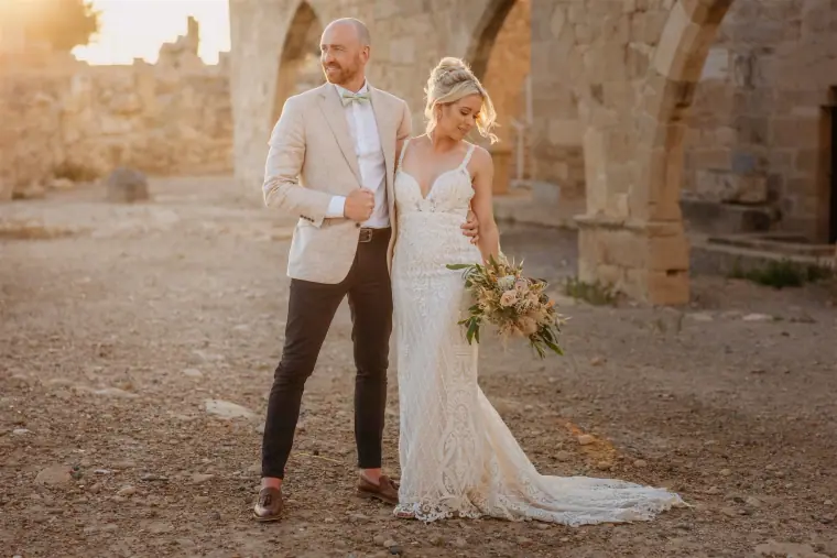 Sarah and Ben standing among old stone arches in golden light