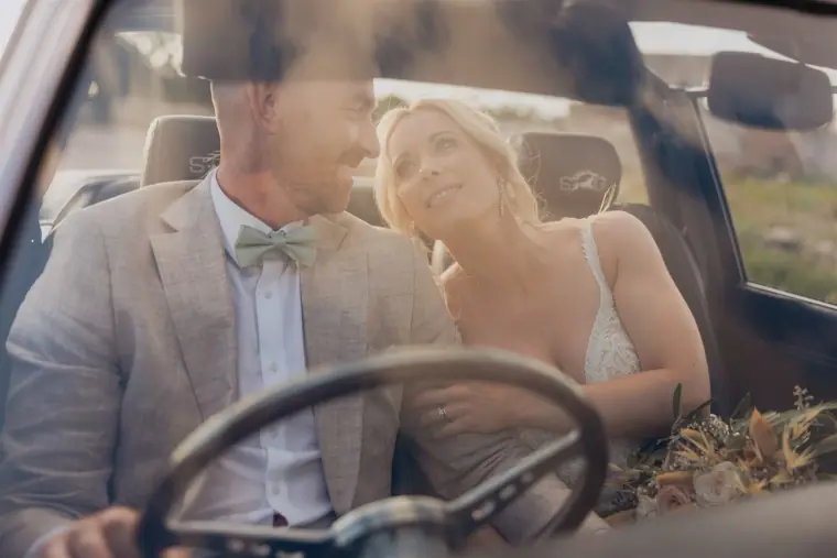 Sarah and Ben seen through the windscreen of the convertible, Ben at the wheel
