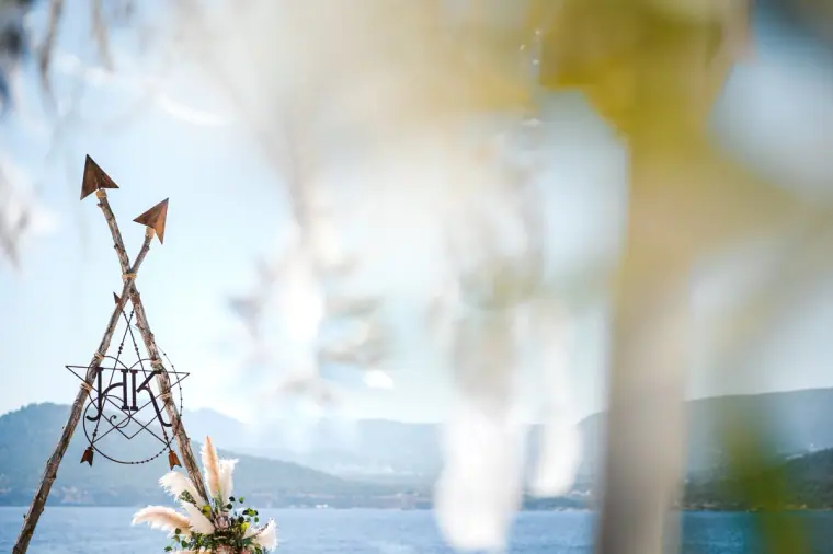 Monogrammed tipi arch with arrows against the blurred sea