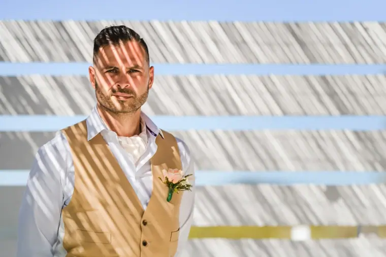 Kenton in a gold waistcoat, striped shadows falling across him
