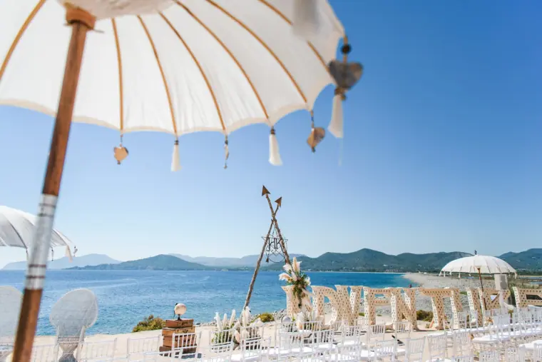 Fringed parasols and white chairs set for a beach ceremony at Experimental Beach