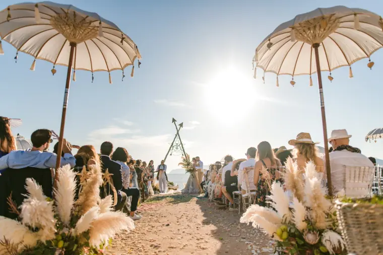 Guests seated between tasselled parasols and pampas grass on the beach aisle