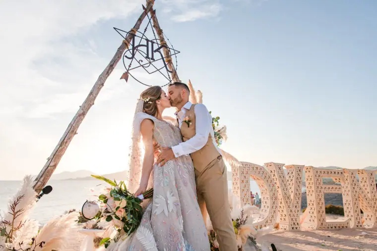 Couple kissing under the tipi arch beside giant ADVENTURE letters at Experimental Beach