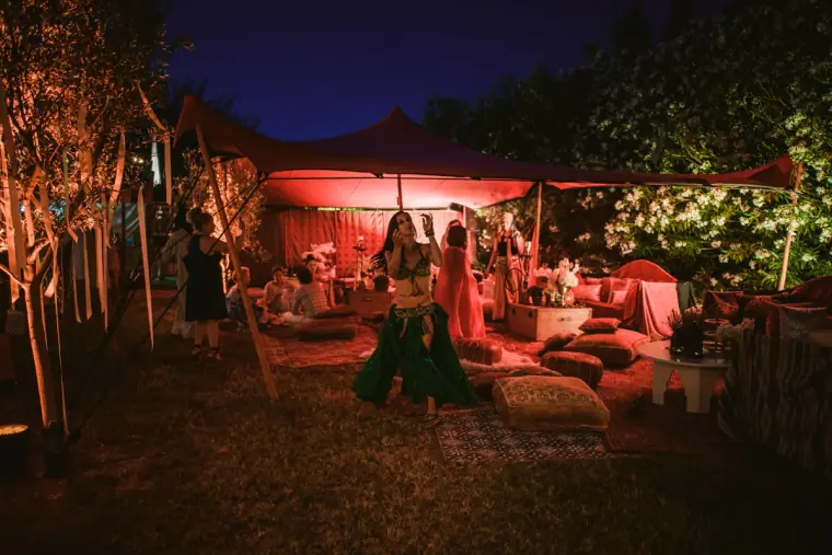 Lounge area with floor cushions and rugs glowing under coloured lights
