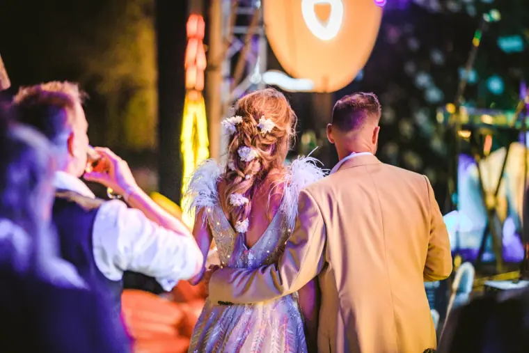 Bride and groom watching a show in front of a stage lit in orange