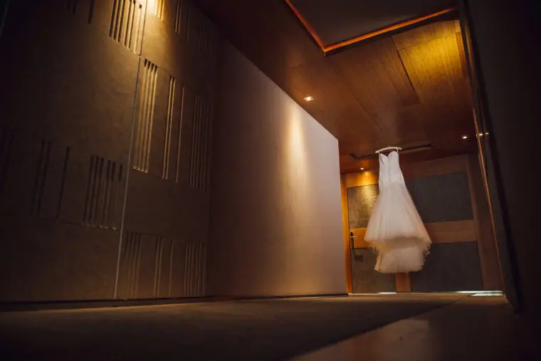 Wedding dress hanging in a dark wood-panelled hotel room