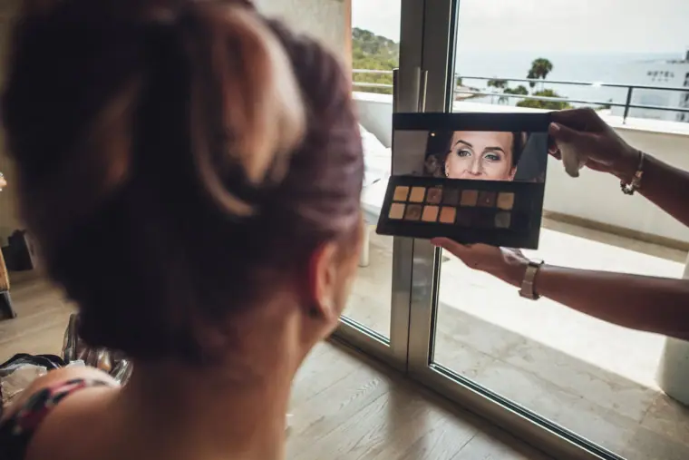 Bride seen from behind as a make-up artist holds up an eyeshadow palette