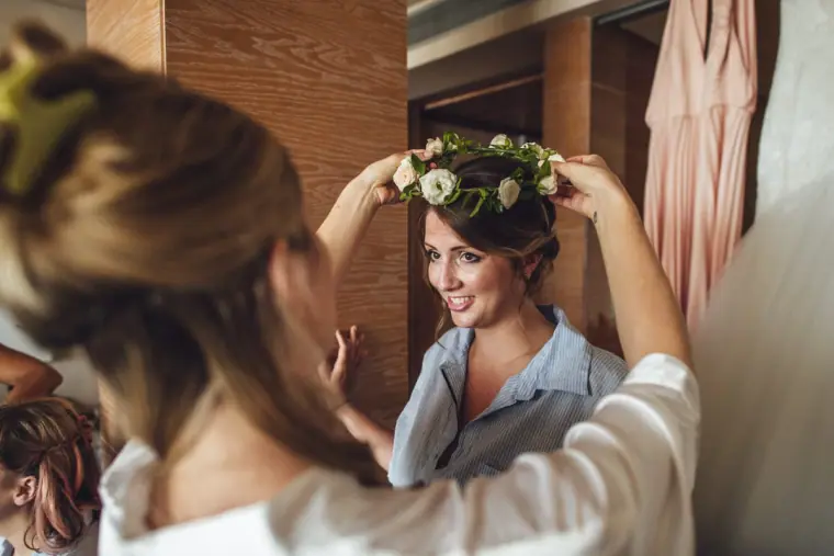 Bridesmaid placing a flower crown on another bridesmaid's head