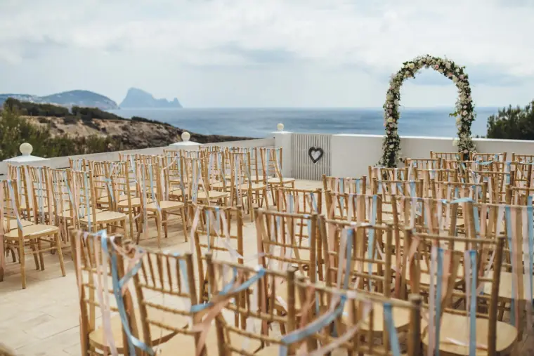 Rows of gold chairs and a floral arch overlooking the sea at Elixir Shore Club