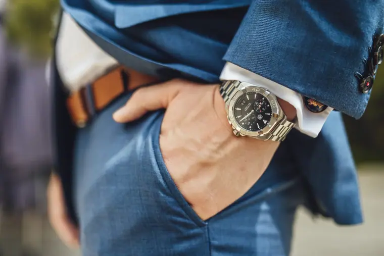 Groom's hand in his pocket showing a silver watch and tan belt