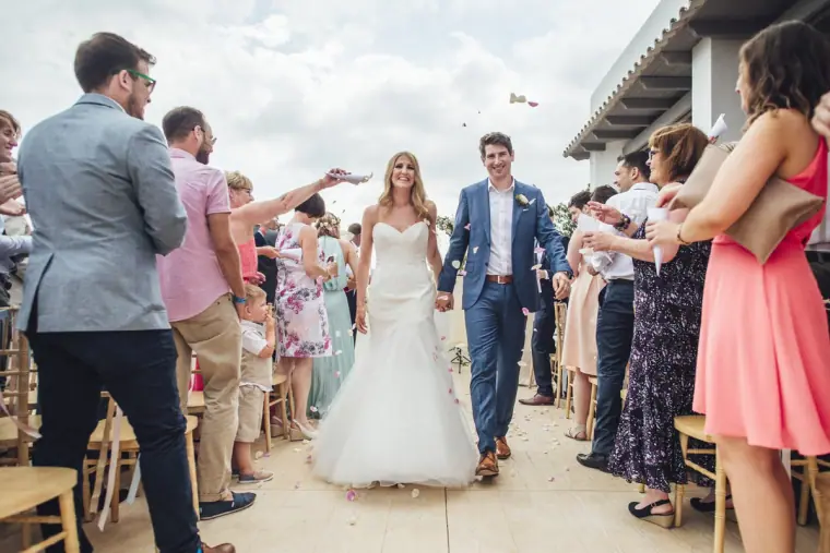 Newlyweds walking back up the aisle as guests throw petals