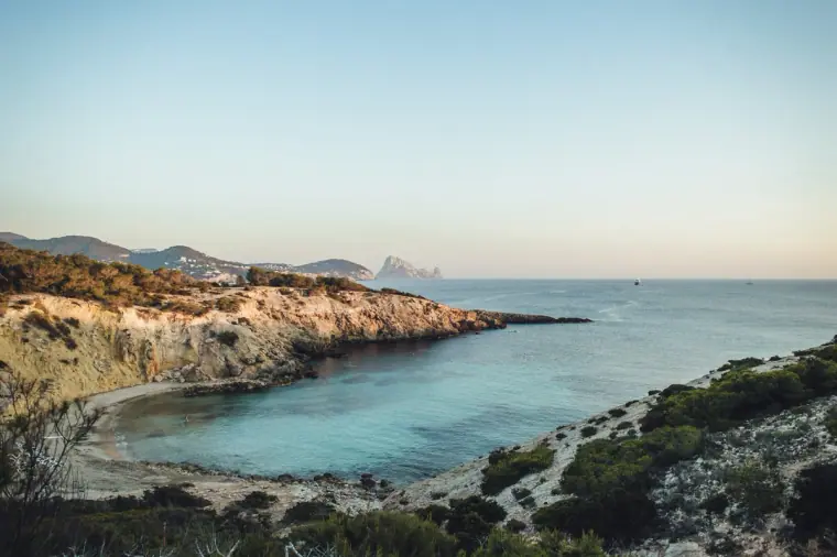 Turquoise cove beneath rocky cliffs in the golden evening light