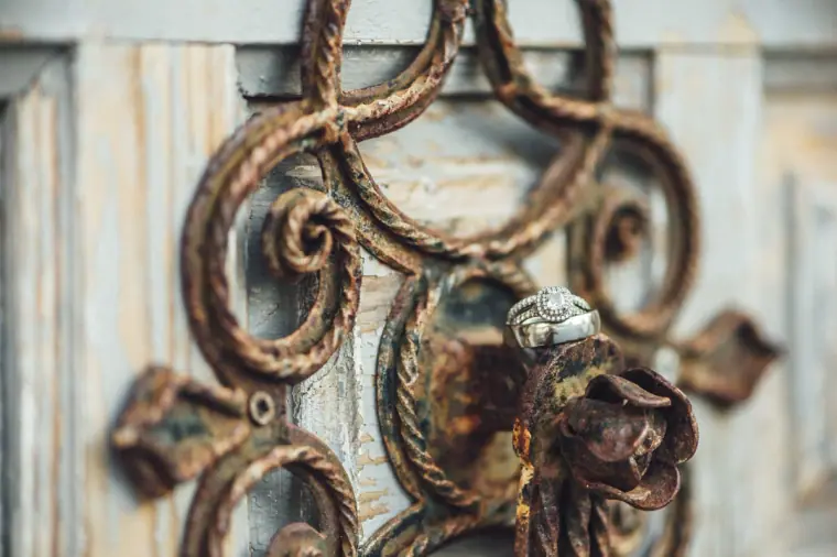 Gold wedding rings hanging on an ornate rusted iron door handle