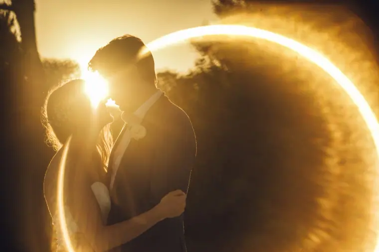 Stephanie and Paul kissing inside a golden ring of sun flare at Elixir Shore Club, Ibiza