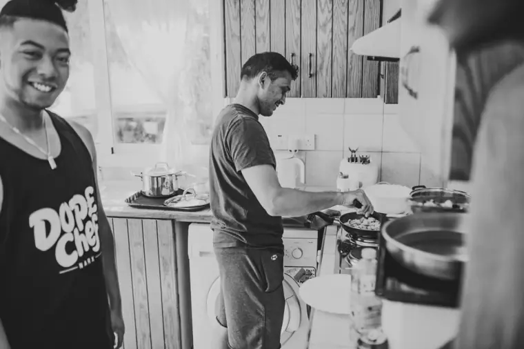 Black-and-white photo of the groom's friends cooking breakfast in the villa kitchen
