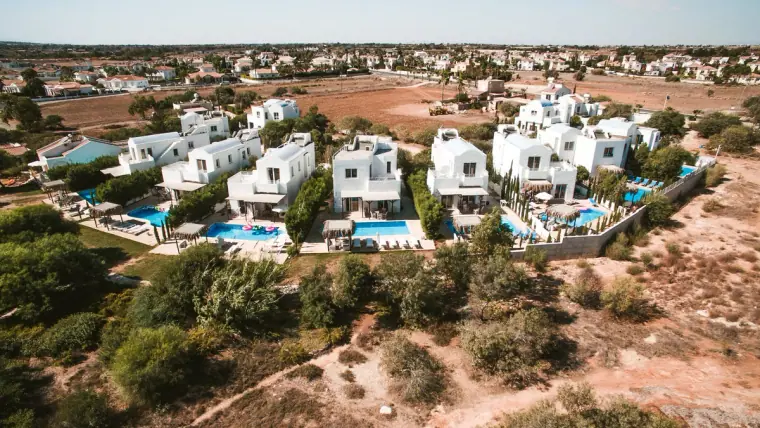 Aerial view of white villas and blue pools at Thalassines Beach Villas, Ayia Napa