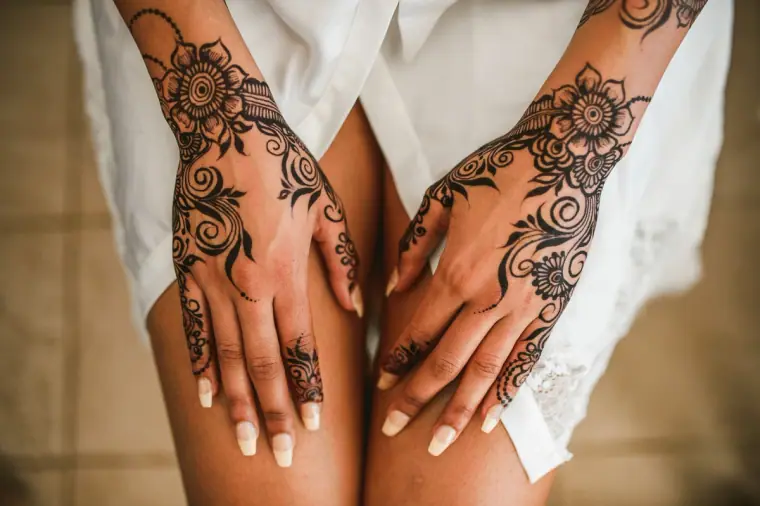 Bride's hands decorated with intricate henna resting on her knees