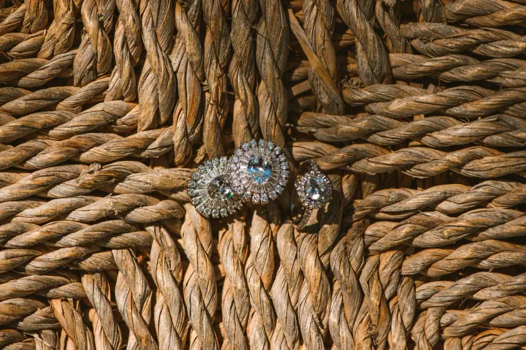 Sparkling bridal earrings resting on a woven rattan surface