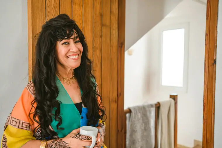 Smiling woman in a colourful patterned top holding a mug in the villa
