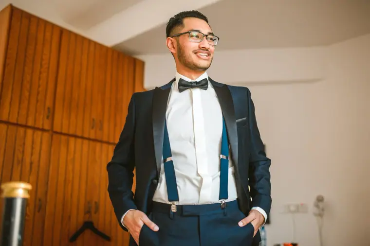 Adhib smiling in a navy tuxedo jacket, bow tie and braces before the ceremony