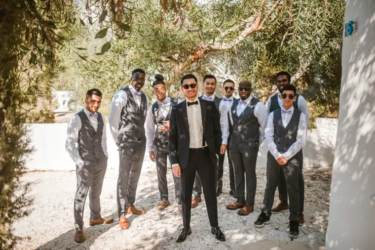 Groom and groomsmen in grey waistcoats lined up in the villa garden