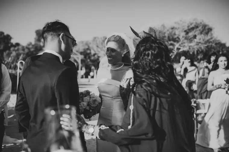 Black-and-white photo of the groom greeting the bride at the end of the aisle